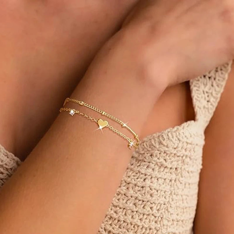 Two delicate 14k gold-plated bracelets with a heart pendant.