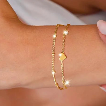 Two delicate 14k gold-plated bracelets with a heart pendant.