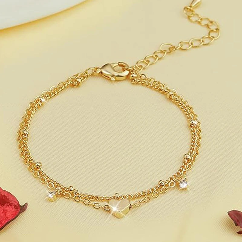 Two delicate 14k gold-plated bracelets with a heart pendant.